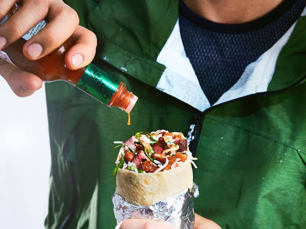 man pouring Tabasco on a Chipotle burrito