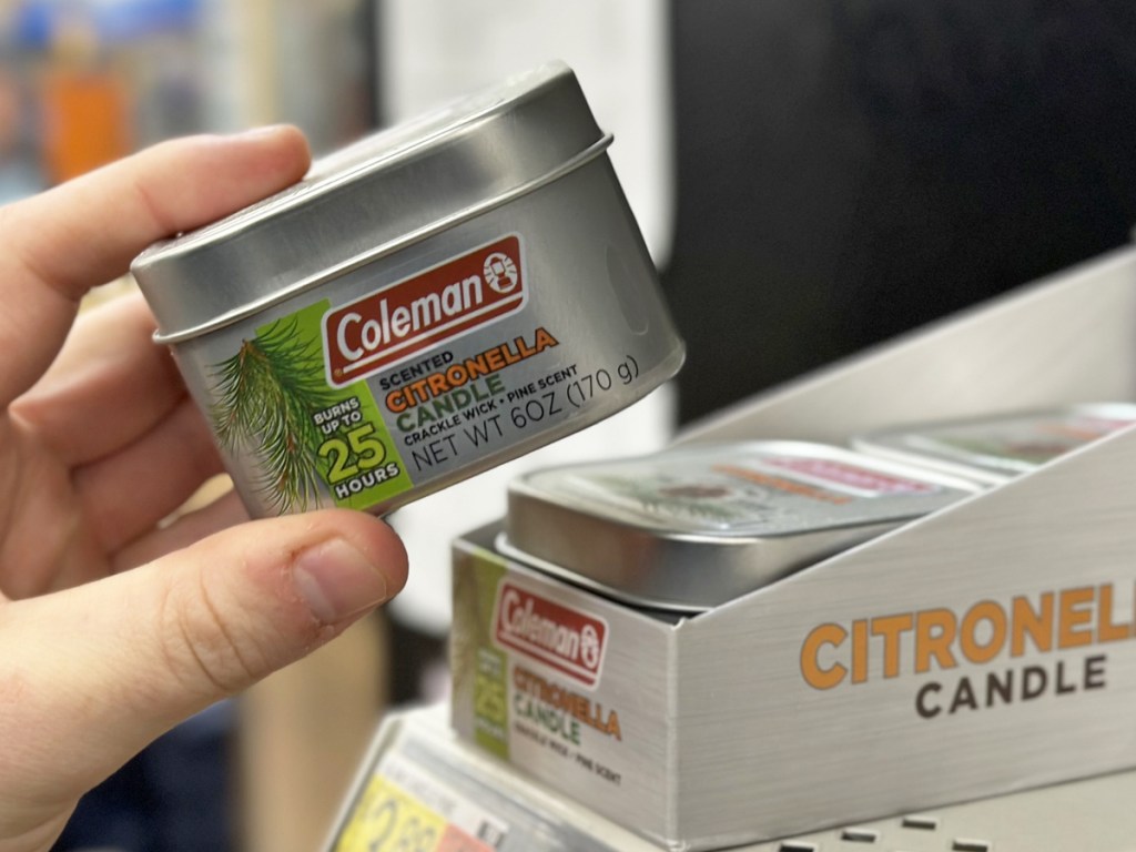 hand picking up Coleman Citronella Candle from store shelf