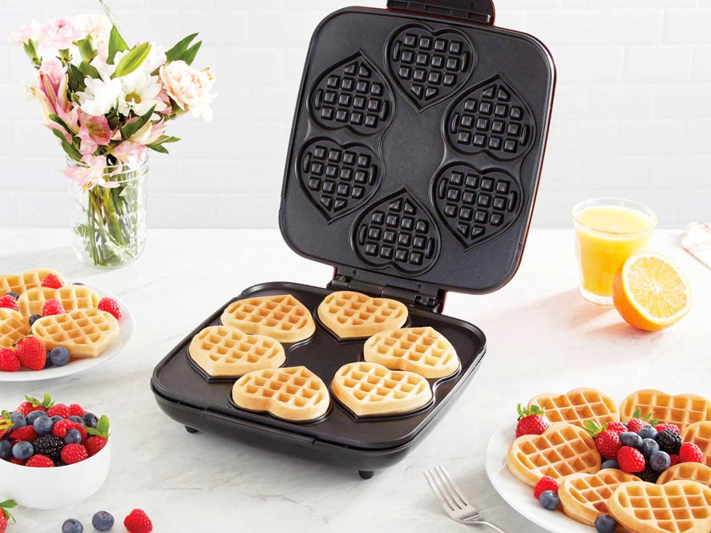 6 waffles on plate of waffle maker near plates of waffles with fruit