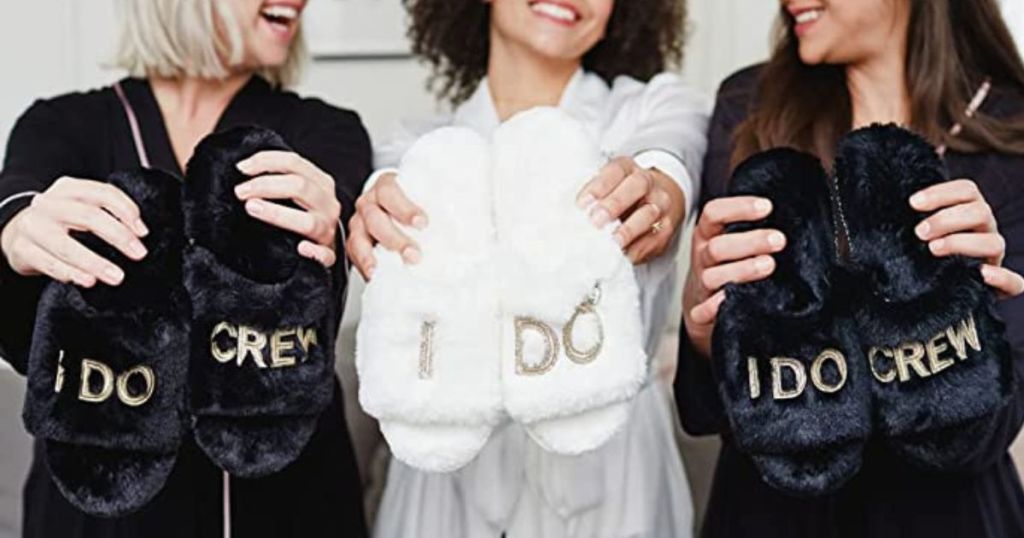 bride and two bridesmaid holding up Dearfoams bridal slippers in front of them