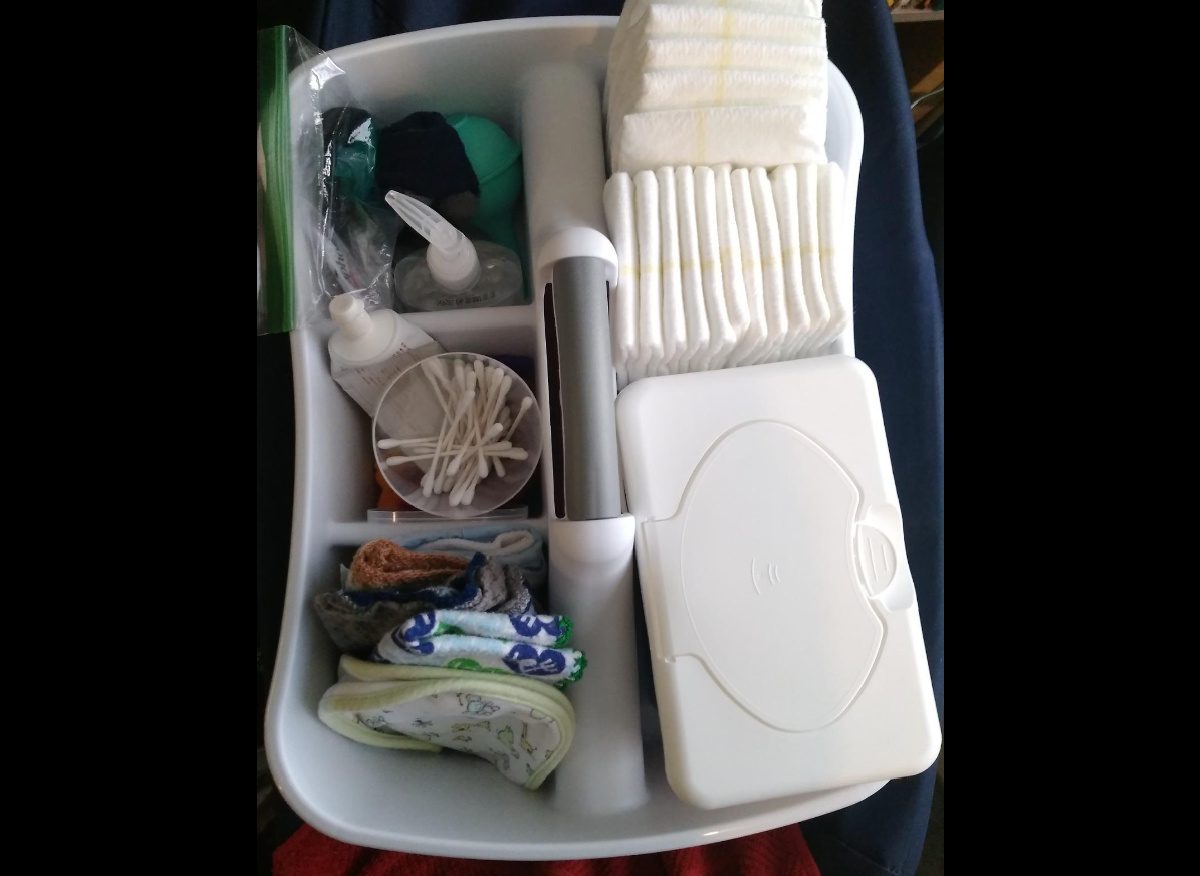 white plastic caddy being used to hold diaper changing supplies