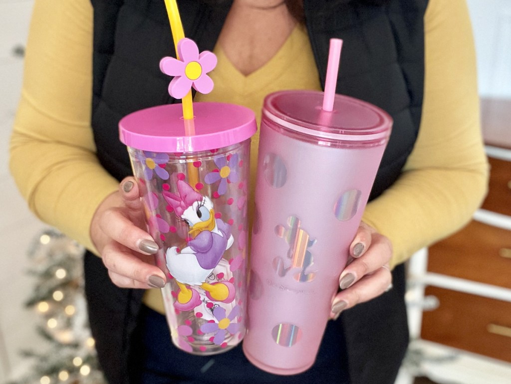 woman holding two pink disney tumblers