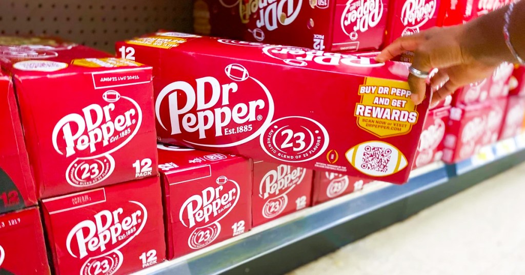 hand grabbing box of dr pepper cans from shelf