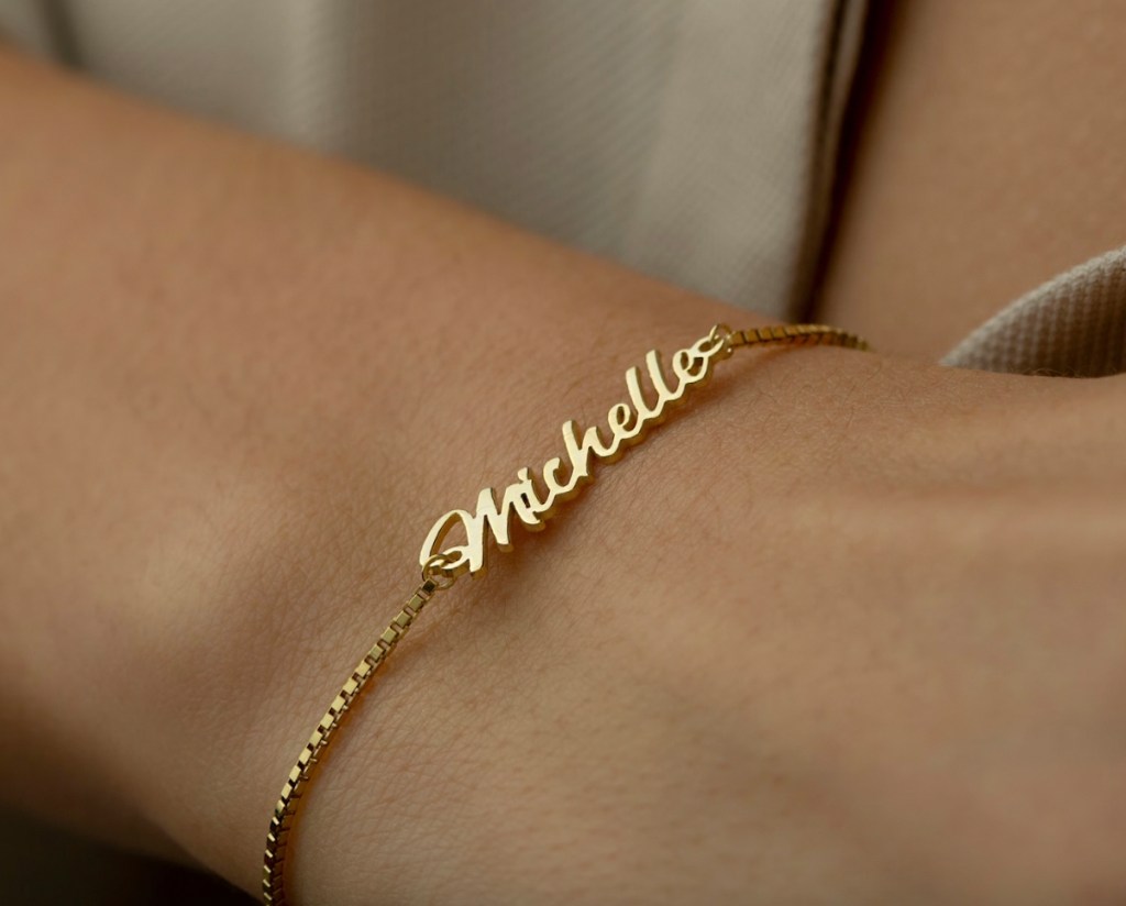 close up of hand wearing a gold michelle name bracelet