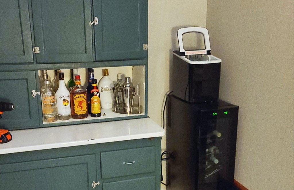 home bar set up with black ice maker on top of wine fridge