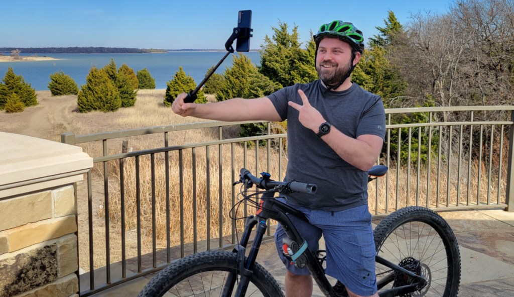 Man outdoors on bike holding a Gimbal Stabilizer Selfie Stick