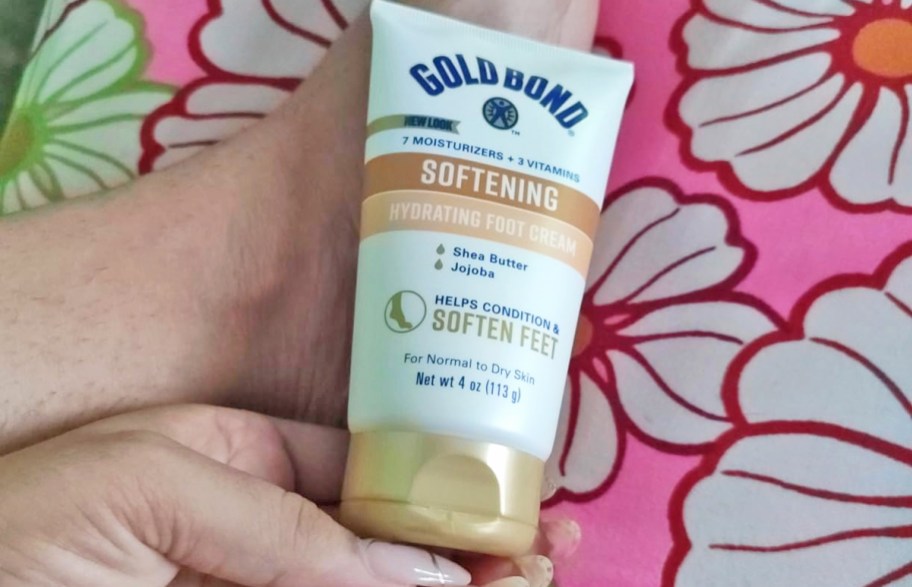 hand holding a bottle of Gold Bond Softening Foot Cream
