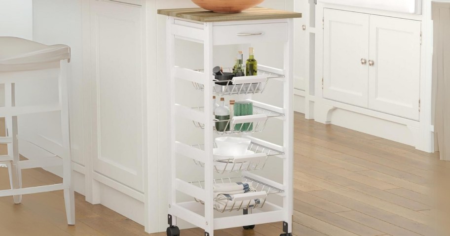 white wooden kitchen storage cart with wire basket pull outs sitting in a kitchen