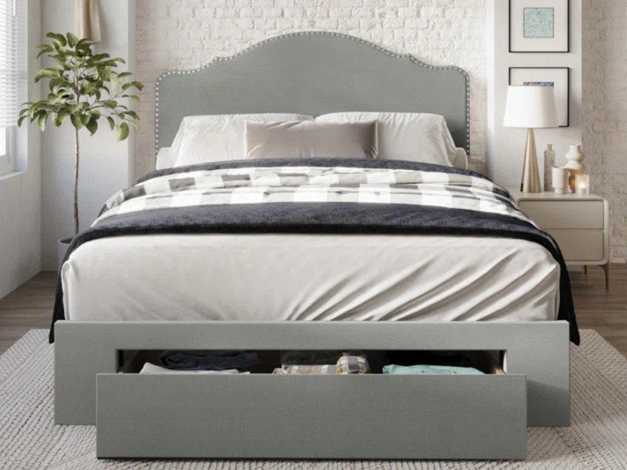 a grey upholstered bedframe and headboard with storage drawers at the front in a bedroom