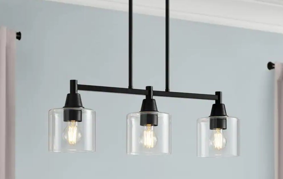 Light fixture hanging from the ceiling with three lights encased in glass.