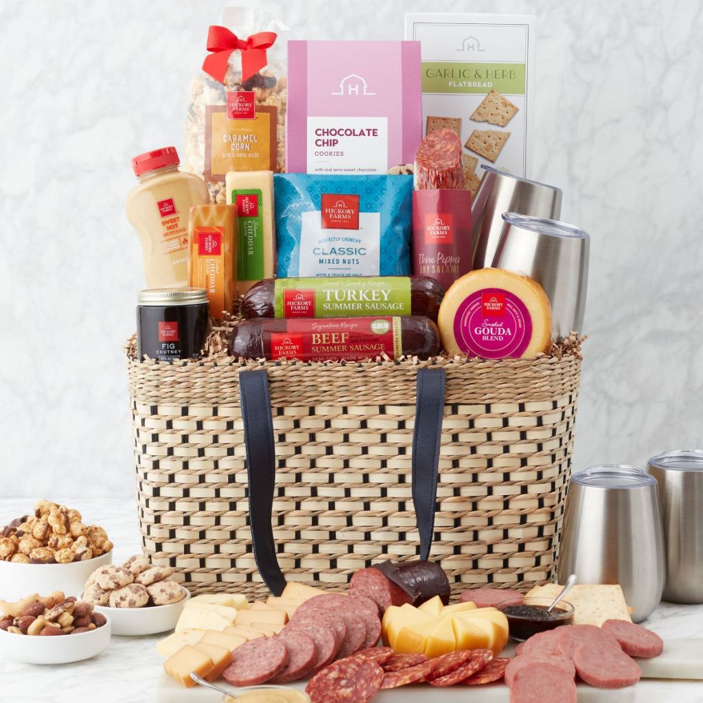 Picnic basket filled with food and summer sausage and cheese in front of the basket