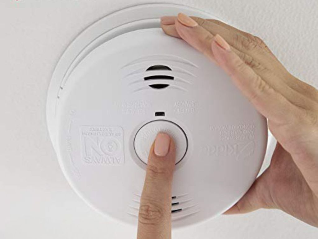 Kidde Smoke & Carbon Monoxide Detector, 10-Year Battery, Voice Alerts shown on ceiling with hands setting it
