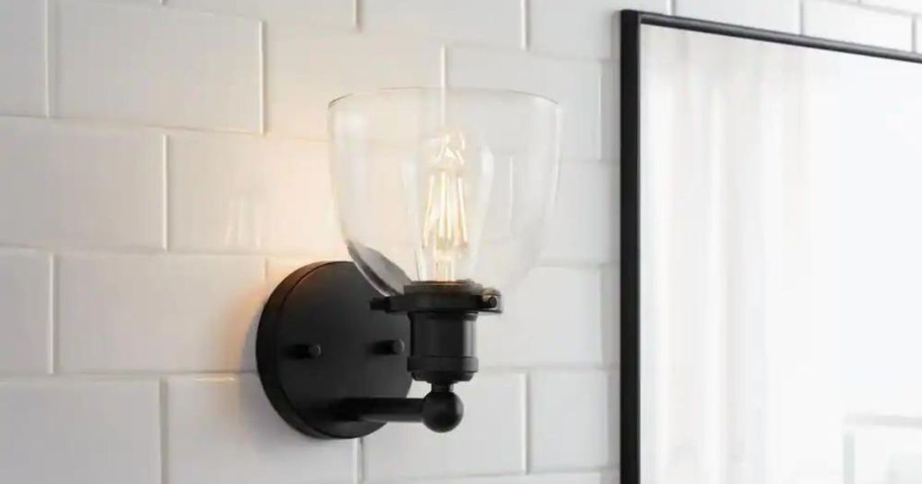 Black wall sconce with a glass shade hanging next to a picture.