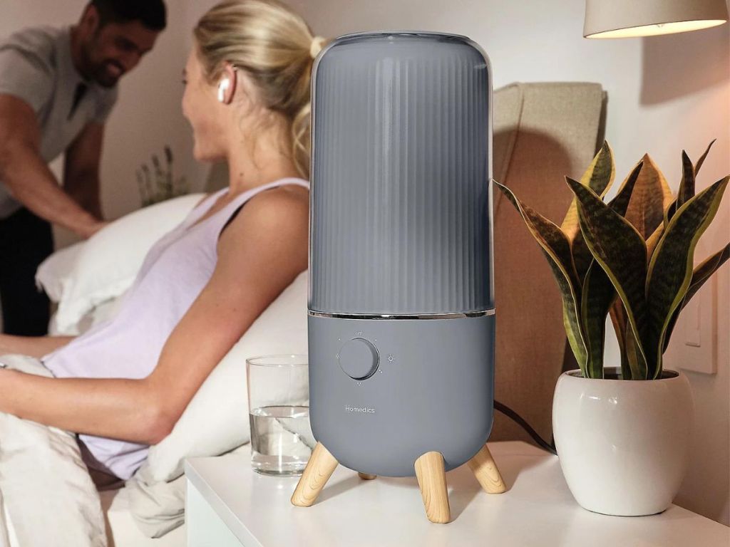woman laying in bed next to gray humidifier