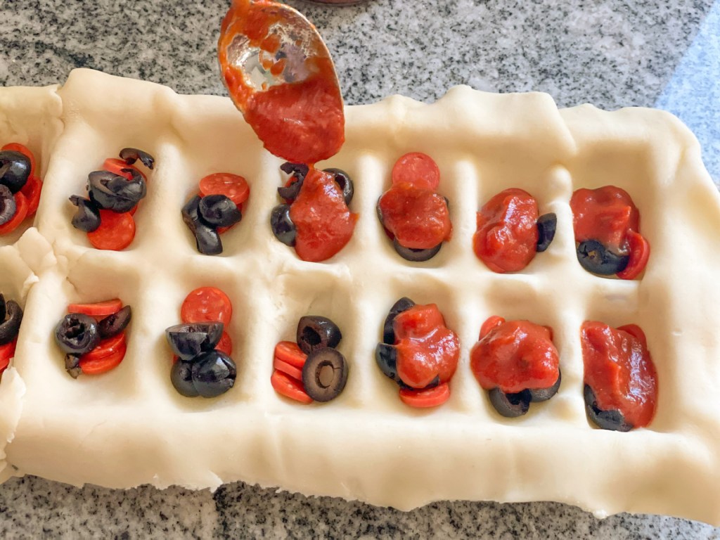 adding sauce to pie dough in ice cube tray