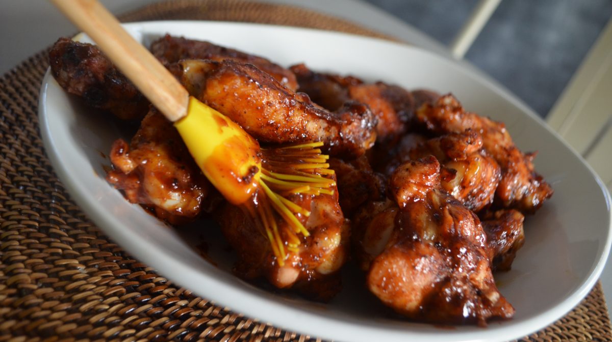 brushing marinade on Honey bbq chicken wings, one of our favorite gameday recipes