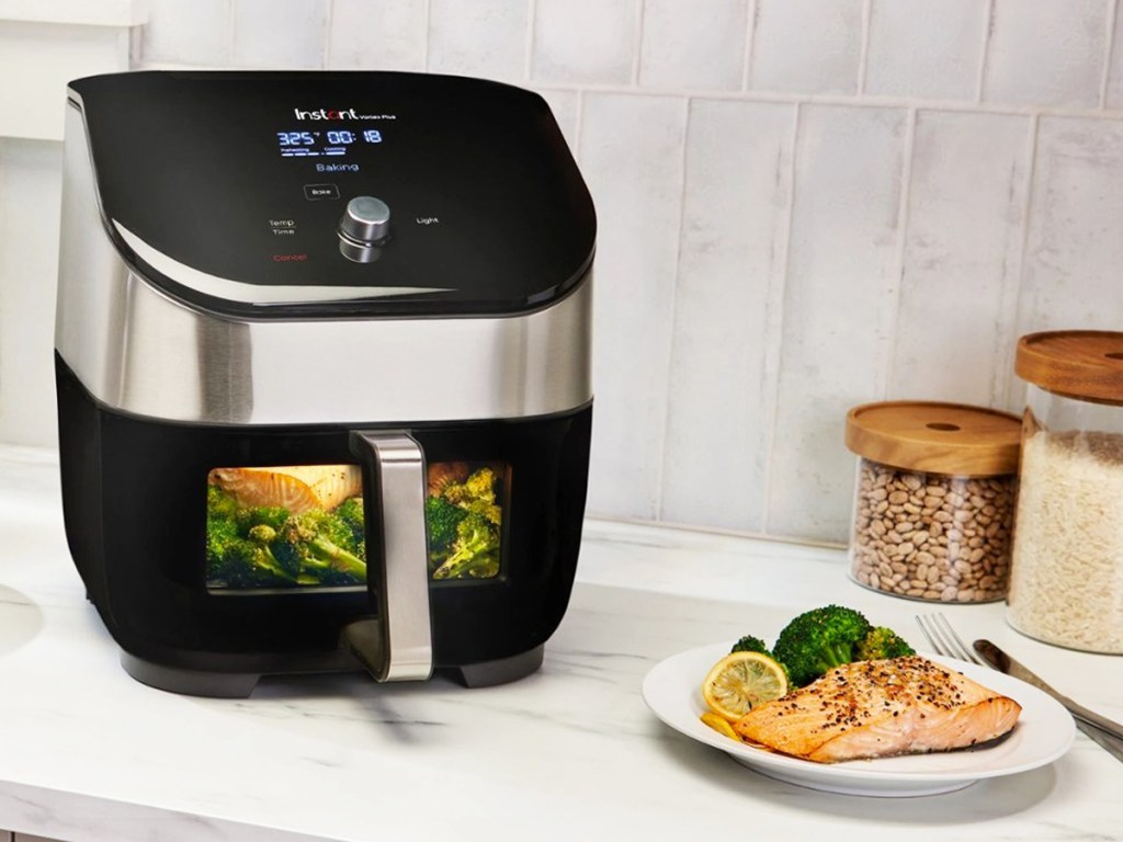 black & stainless steel air fryer on counter next to plate of salmon and broccoli