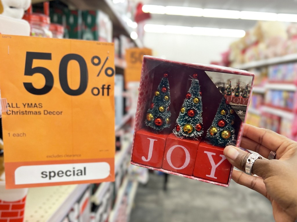 hand holding set of blocks that spell joy with christmas trees on top