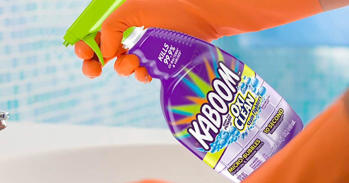 A person wearing gloves, cleaning a bathroom with Kaboom Cleaner