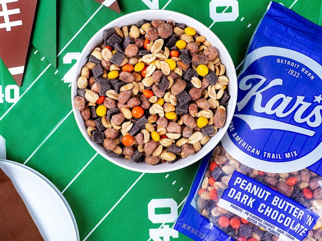 Kar's Nuts Peanut Butter ‘n Dark Chocolate Trail Mix 2 in bowl and bag on football themed table cloth