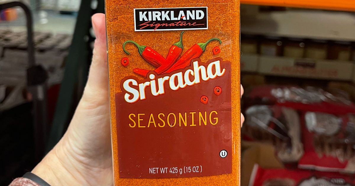 a hand holding a bottle of Kirkland's signature Sriracha seasoning