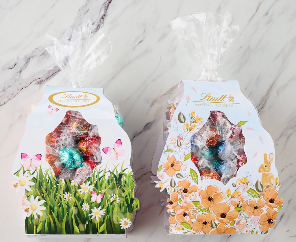 A bag with grass and flowers printed on it and a bag with flowers printed on it both full of Lindt Lindor truffles