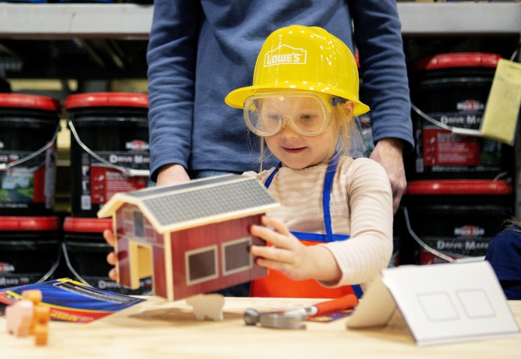 girl building a toy barn