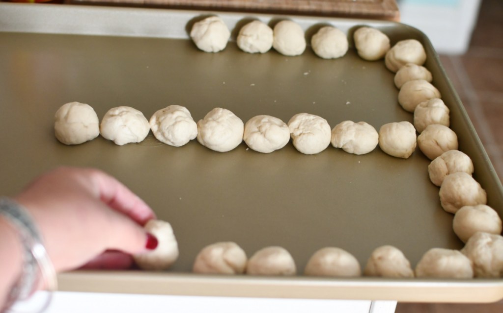placing rolled balls of dough onto a sheet pan in order to make 4 cheese dip