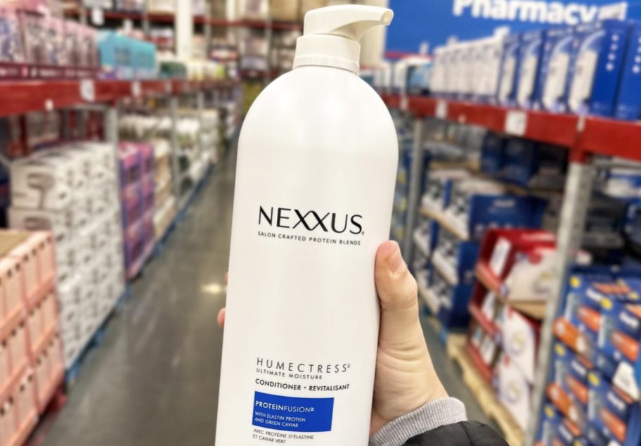 hand holding up white bottle of Nexxus Humectress Ultimate Moisture Conditioner
