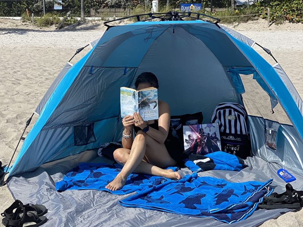 Woman reading a book inside an Oileus X-Large 4 Person Beach Tent Sun Shelter 