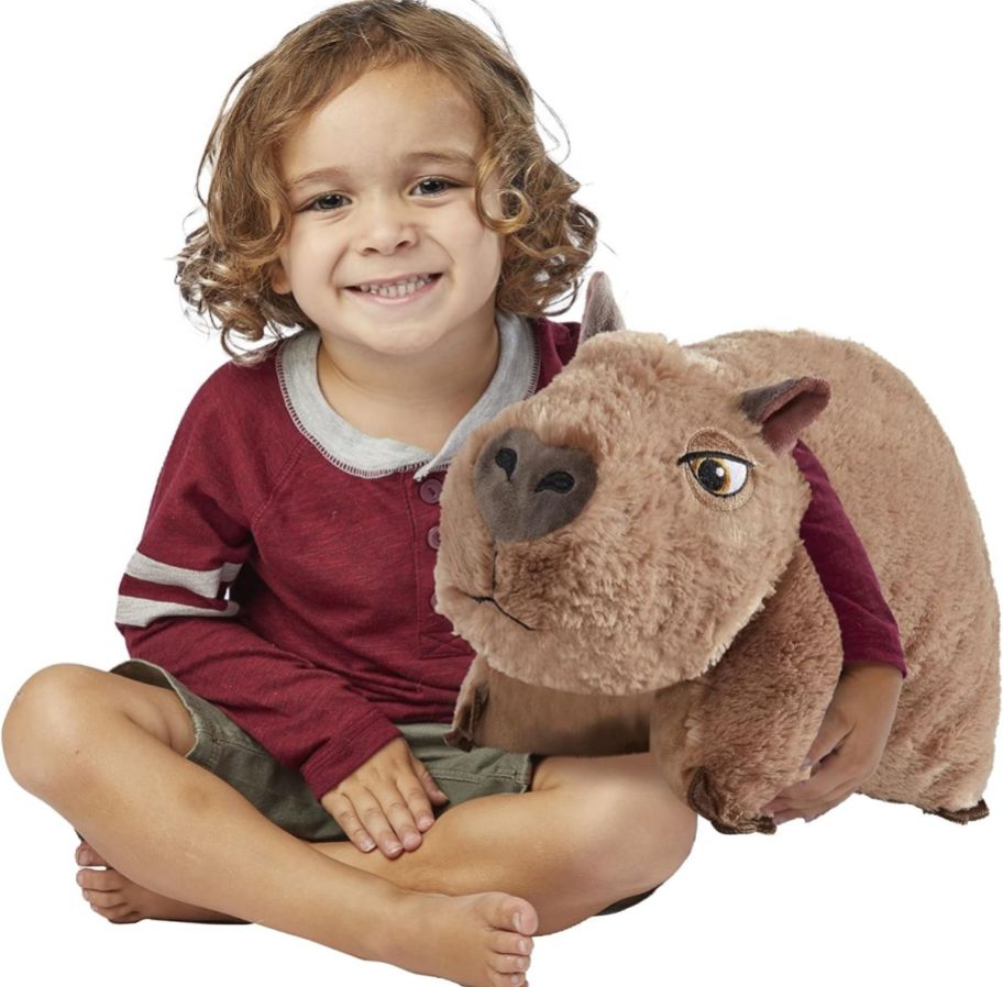 a little boy holding a Pillow Pets Disney Encanto Capybara 16 StuffedPlush