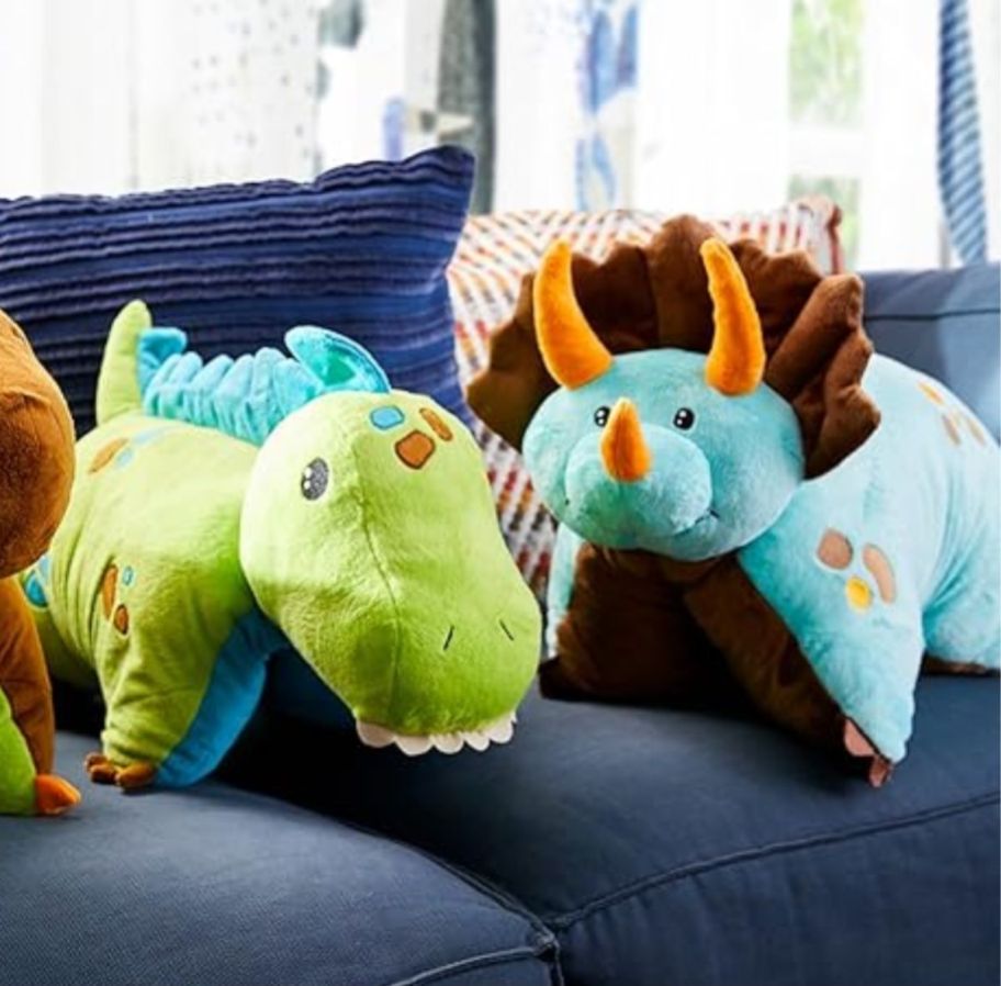 two dinosaur pillow pets on a sofa