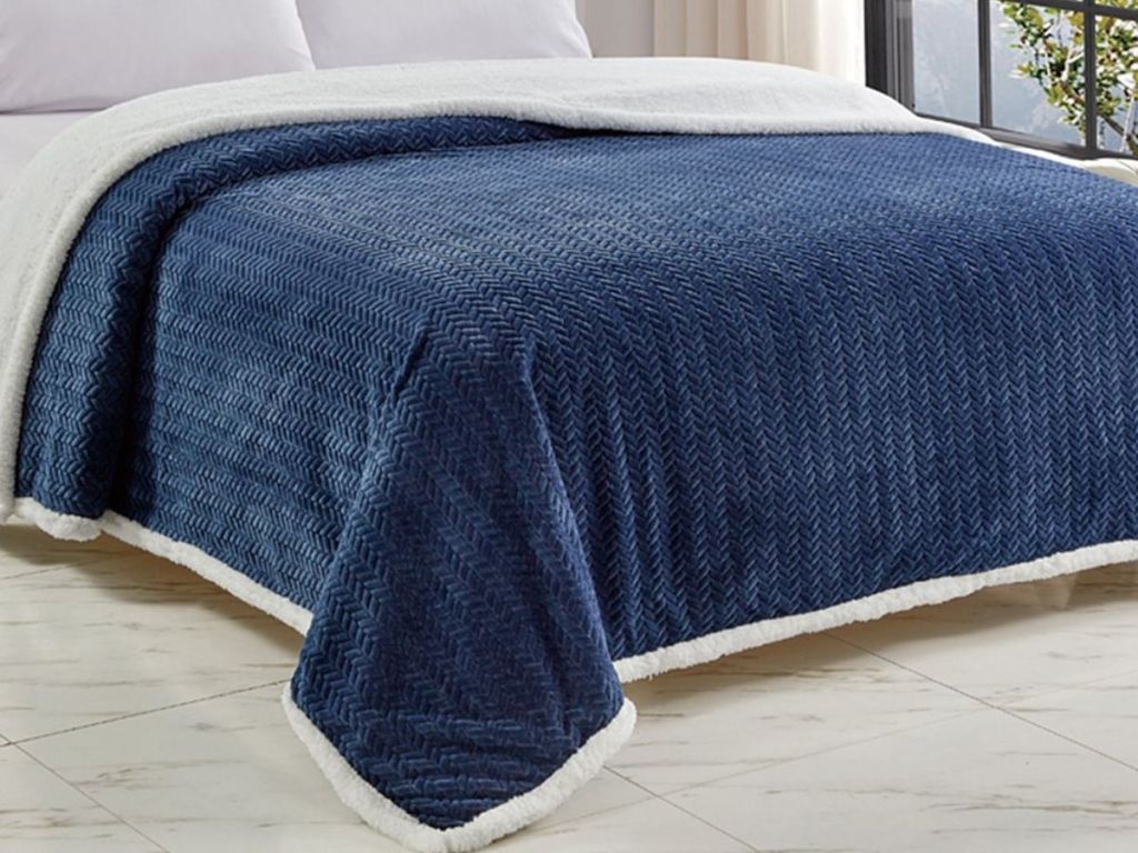 A bed with a blue sherpa blanket on it 