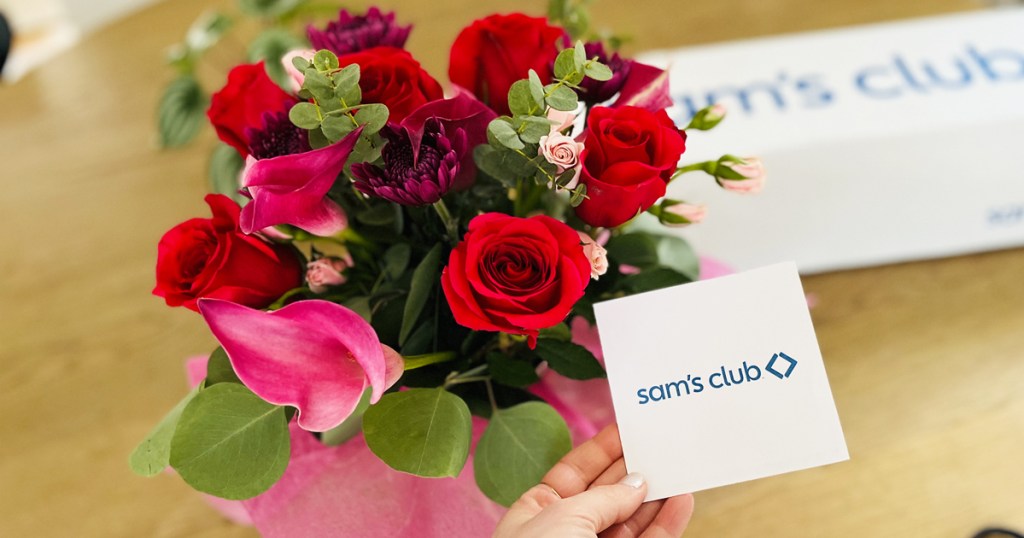 holding sam's club gift note next to bouquet of flowers