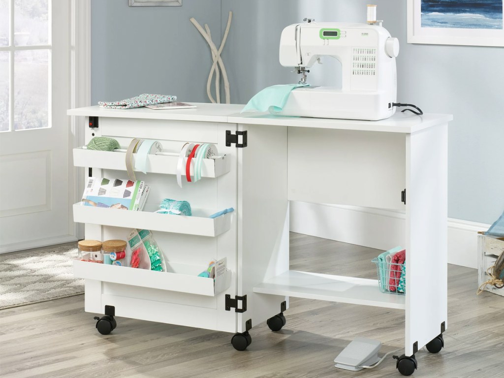 white craft cart with three storage bins on door and sewing machine on top