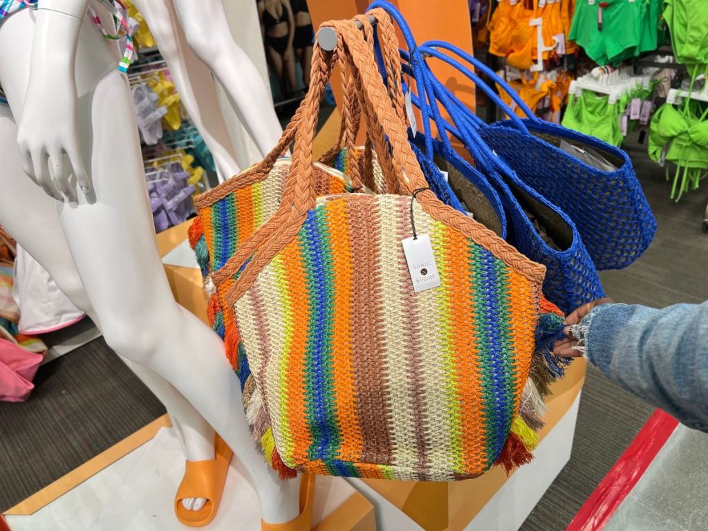 rainbow Shade & Shores straw tote bag and blue tote bags hanging in store