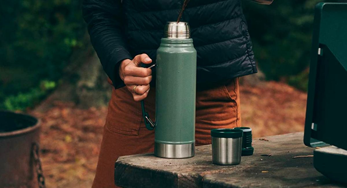 a womans hand holding a Stanley thermos