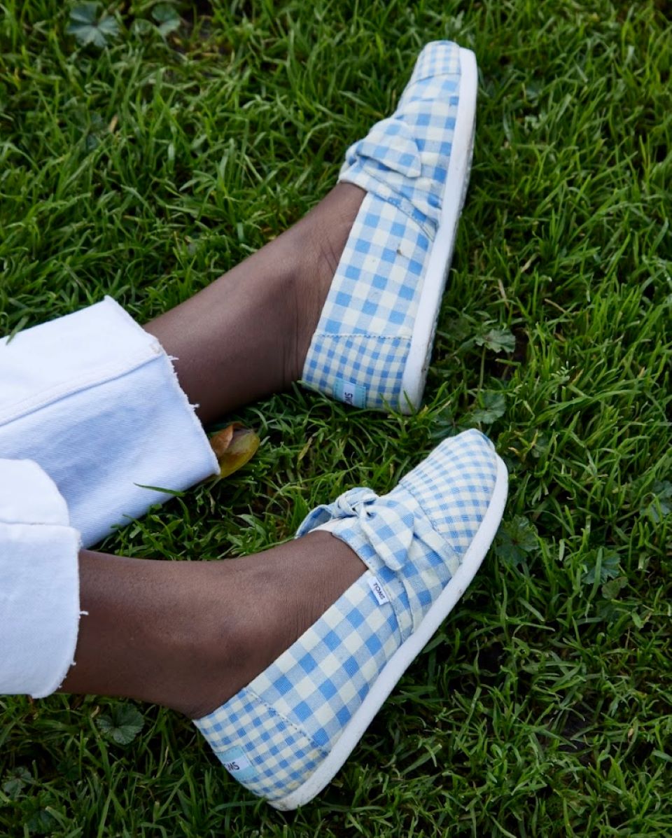 Person wearing a pair of TOMS Gingham shoes while sitting on the grass