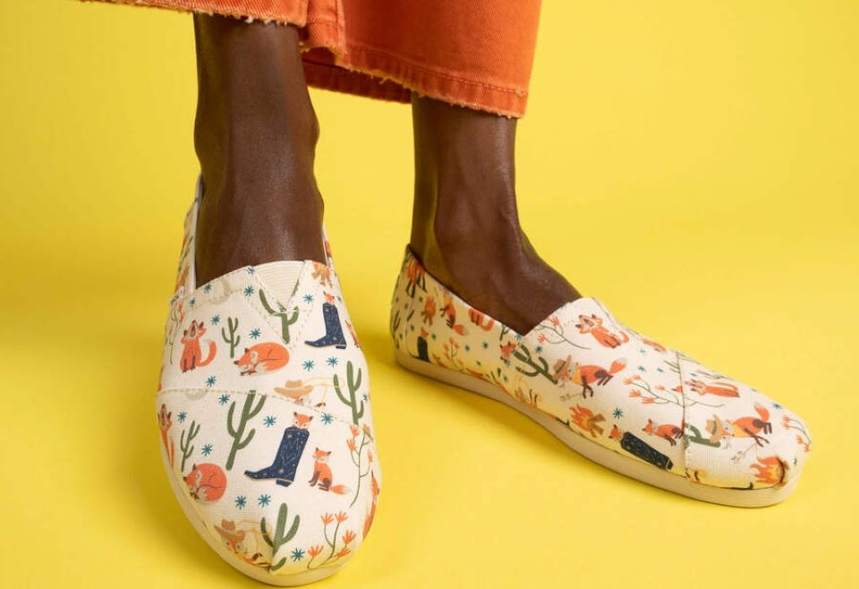 A woman wearing TOMS shoes with foxes on them