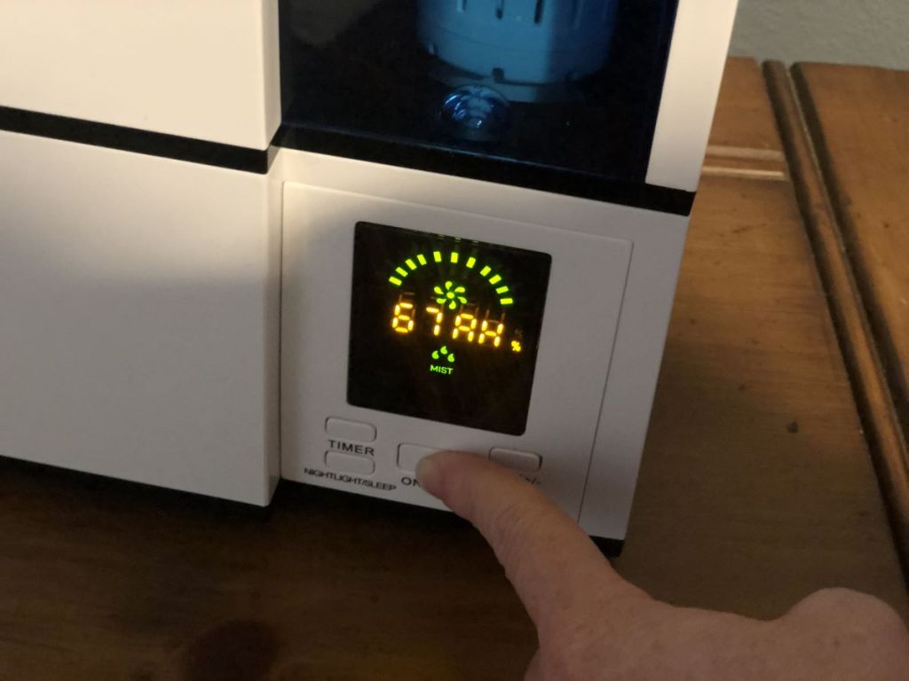 Hand pressing on a button on a humidifier