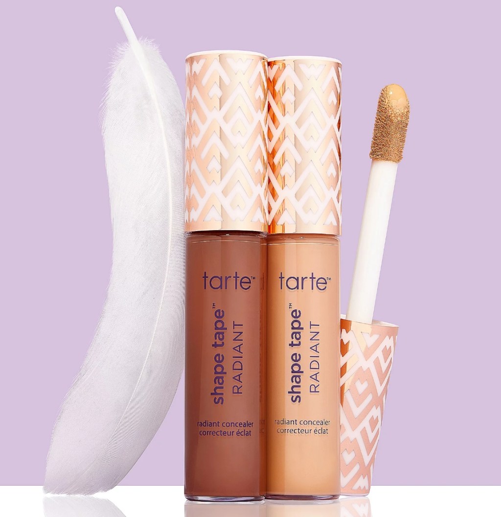 Two tubes of Tarte shape tape and a feather