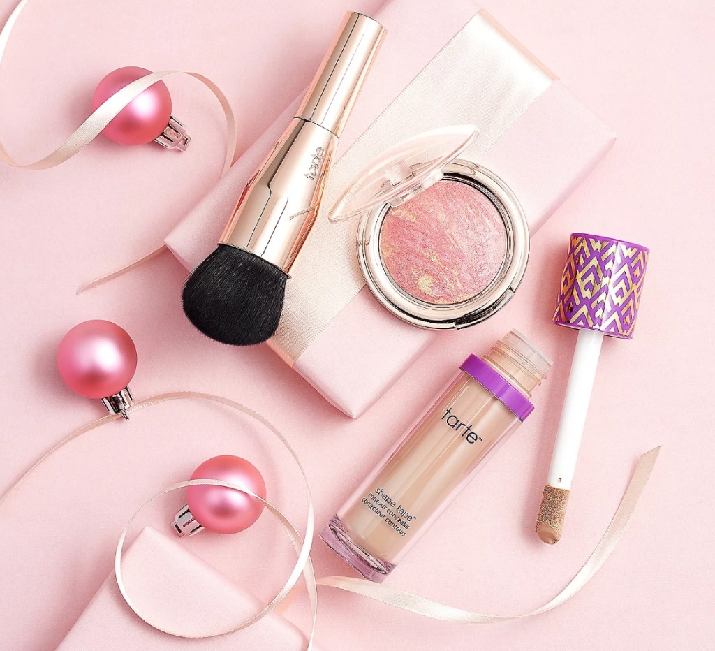Tarte shape tape, blush, and brush surrounded by pink ornaments and ribbon