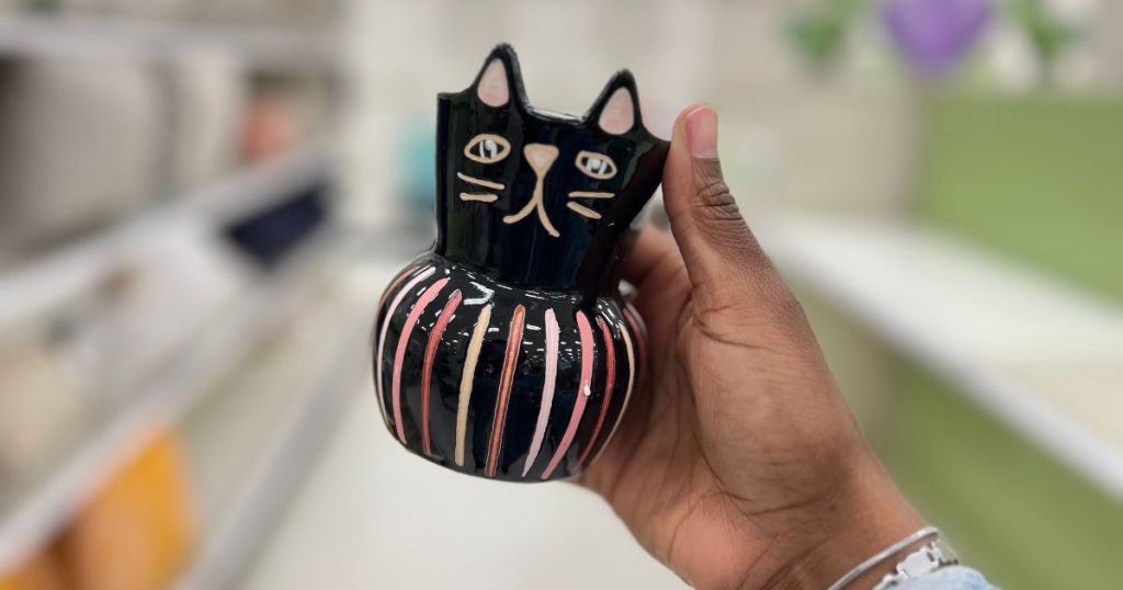hand holding black and neon colored cat planter in store