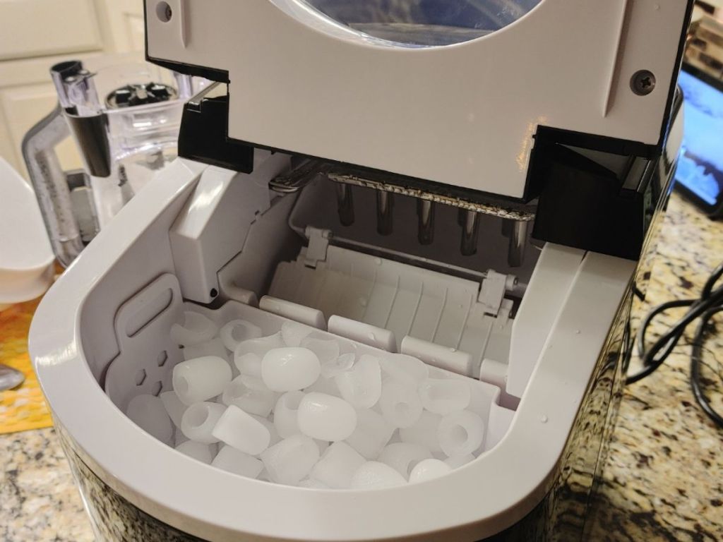 trustech ice maker on counter with lid open exposing a full basket of bullet shaped ice