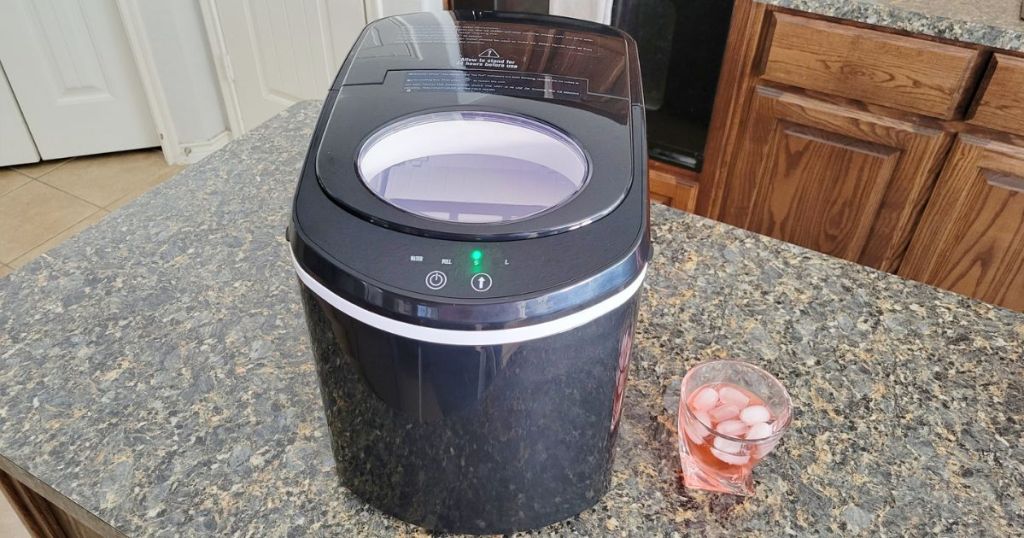 rustech poortable ice maker on counter next to a glass with ice and soda in it