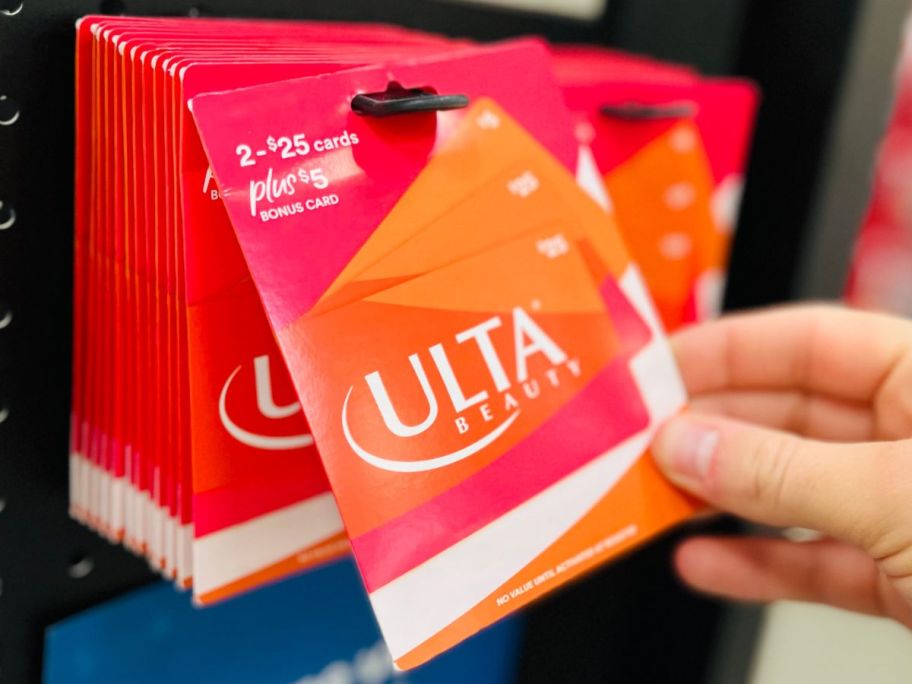 hand taking an ulta gift card from display at sams club