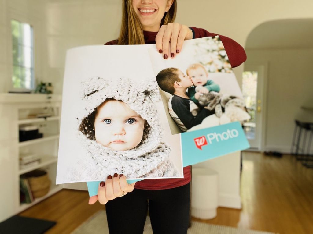 A woman holding up a Walgreens 11X14 wall poster and 8x10 wall poster