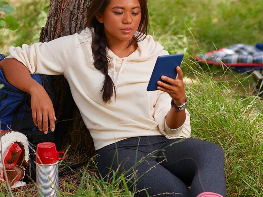 young woman reading on a Kindle outside