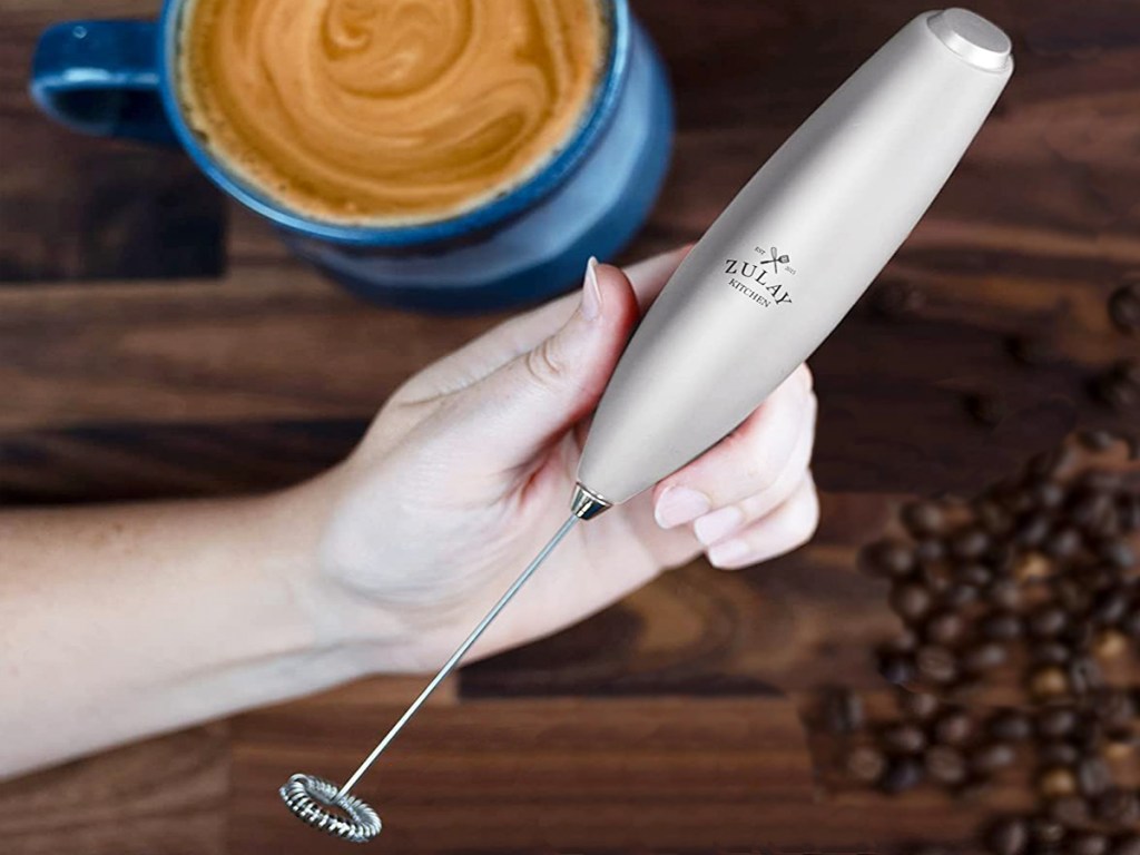 Hand holding silver milk frother