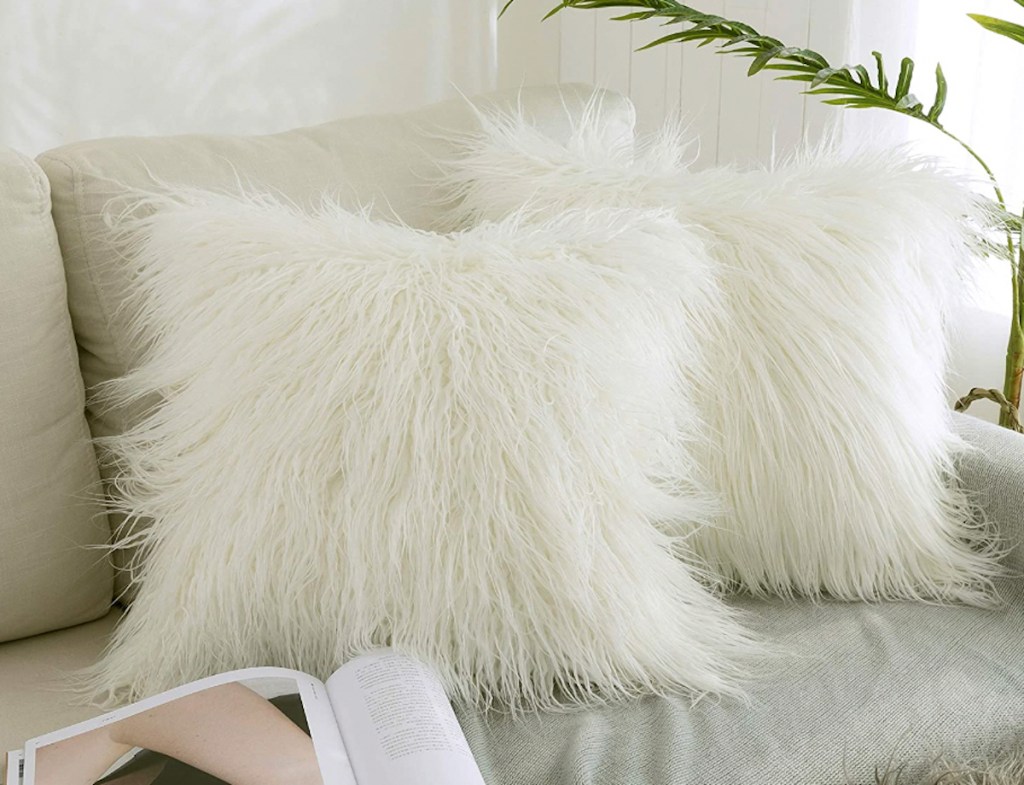 two white faux fur throw pillows on beige couch 